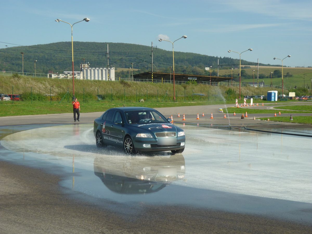 Auto na mokrej kruhovej dráhe, v pozadí inštruktor