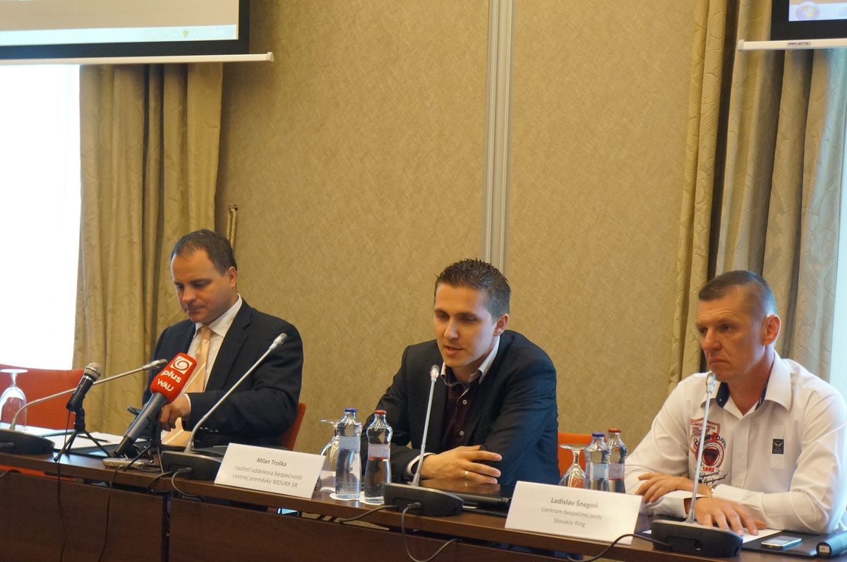 Tlačová konferencia, traja rečníci za stolom s mikrofónmi
