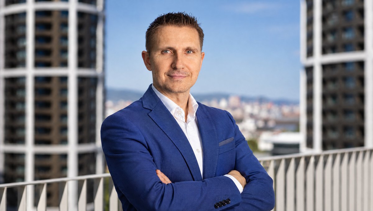 Milan Troška v modrom saku so založenými rukami na terase medzi výškovými budovami